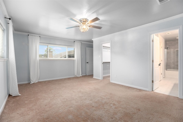 unfurnished bedroom with light carpet, ensuite bathroom, ceiling fan, crown molding, and a spacious closet