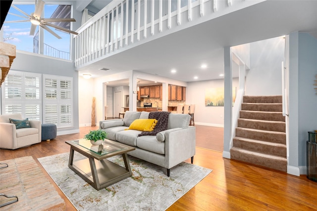 living room featuring a towering ceiling, hardwood / wood-style flooring, and ceiling fan