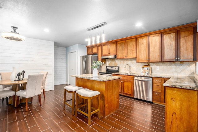 kitchen with sink, a center island, decorative light fixtures, decorative backsplash, and appliances with stainless steel finishes