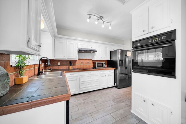 kitchen with white cabinets, sink, backsplash, black appliances, and tile counters