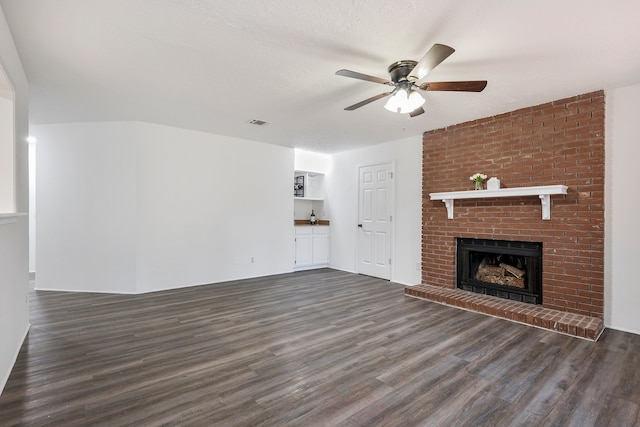 unfurnished living room featuring a brick fireplace, a textured ceiling, dark hardwood / wood-style floors, and ceiling fan