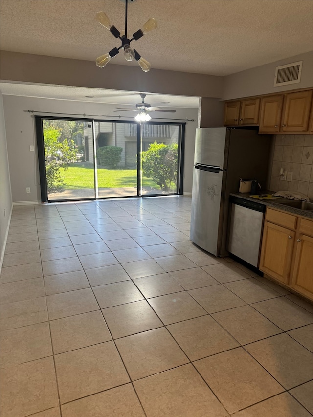 kitchen with decorative backsplash, ceiling fan, light tile patterned floors, a textured ceiling, and appliances with stainless steel finishes