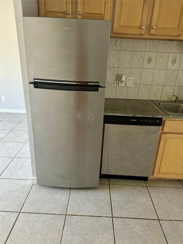 kitchen with backsplash, sink, light tile patterned flooring, and appliances with stainless steel finishes