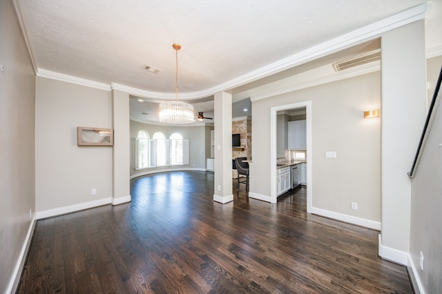 unfurnished room featuring ornamental molding, dark hardwood / wood-style floors, an inviting chandelier, and a stone fireplace