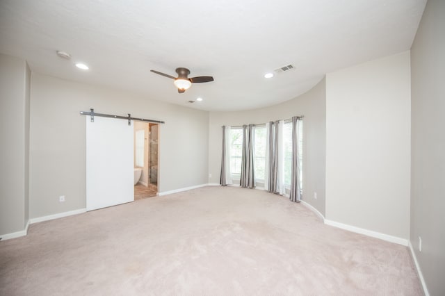 carpeted spare room with a barn door and ceiling fan