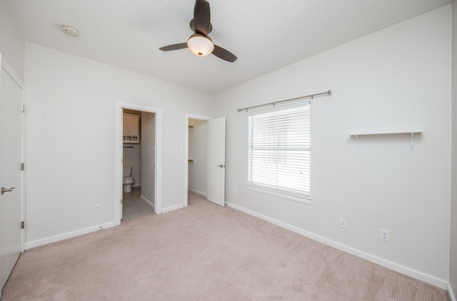 unfurnished bedroom featuring ensuite bath, ceiling fan, and light colored carpet