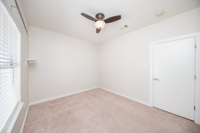 empty room featuring ceiling fan and light colored carpet