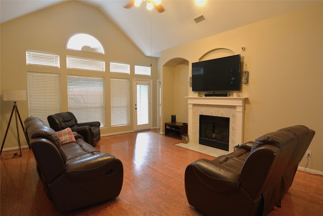 living room featuring a healthy amount of sunlight, wood-type flooring, a tiled fireplace, and ceiling fan