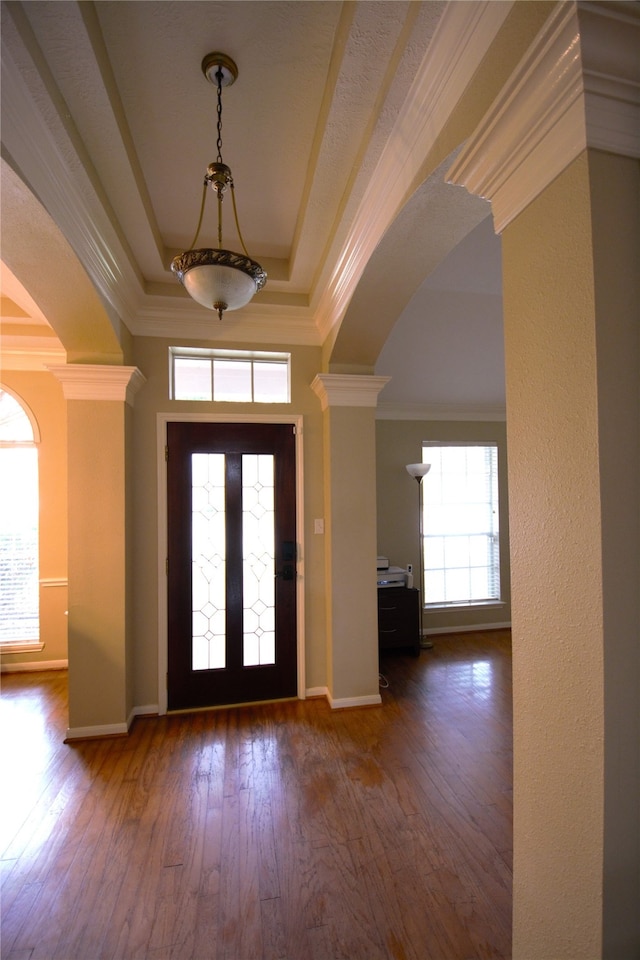 entrance foyer featuring decorative columns, dark hardwood / wood-style flooring, and a wealth of natural light