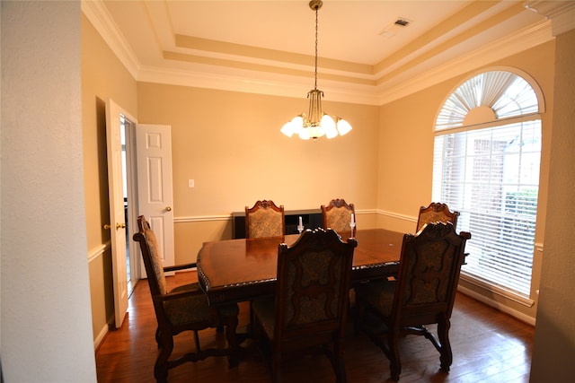 dining space featuring an inviting chandelier, a tray ceiling, dark hardwood / wood-style floors, and ornamental molding