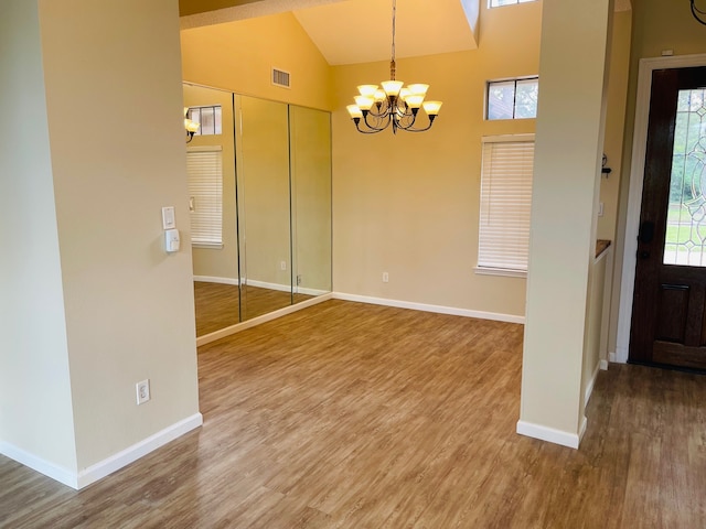 interior space featuring high vaulted ceiling, hardwood / wood-style floors, and a notable chandelier