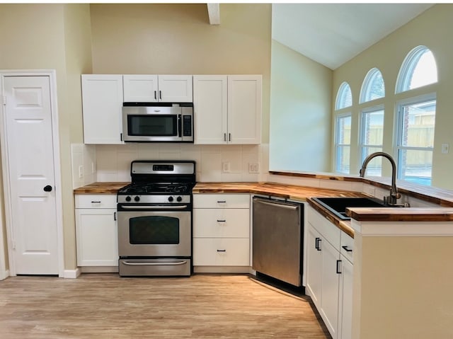 kitchen with lofted ceiling, white cabinets, appliances with stainless steel finishes, and a wealth of natural light