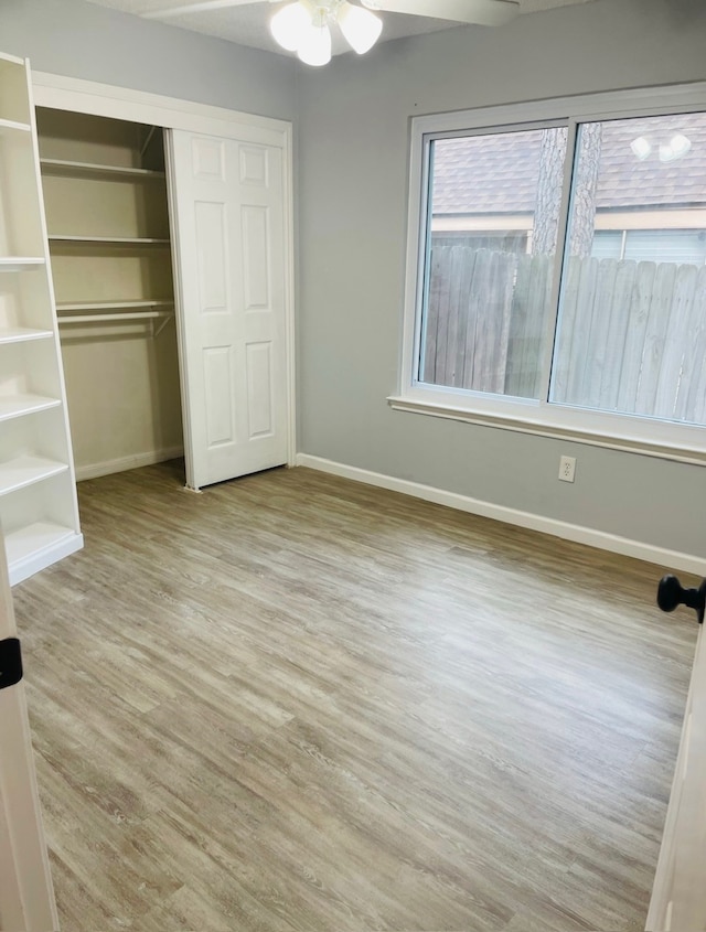 unfurnished bedroom with ceiling fan, light hardwood / wood-style flooring, and a closet