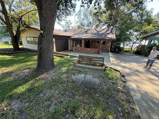 323 Mallard Pt, Livingston, TX 77351 - back of house featuring brick siding, driveway, an attached garage, and covered porch