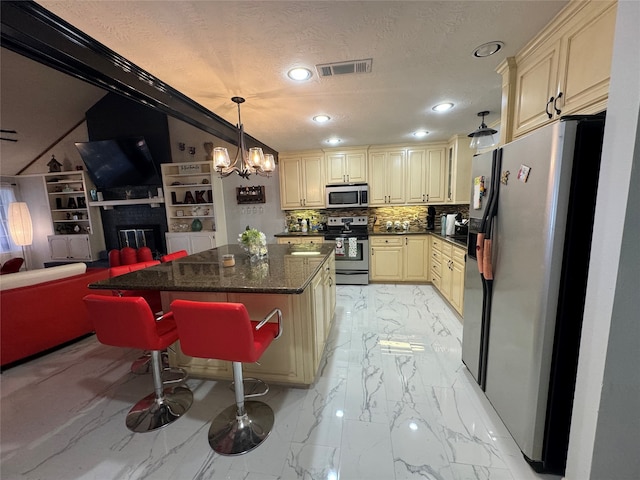 kitchen featuring a kitchen bar, appliances with stainless steel finishes, tasteful backsplash, a kitchen island, and hanging light fixtures