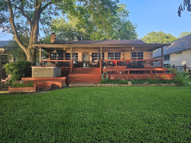 rear view of property with a lawn, a wooden deck, and a hot tub