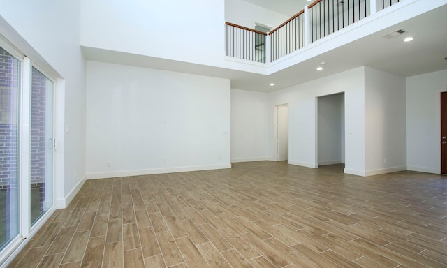 unfurnished living room featuring light wood-type flooring and a high ceiling