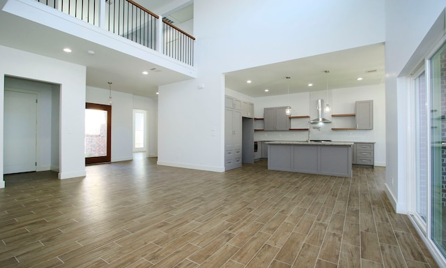 unfurnished living room with wood-type flooring and a towering ceiling