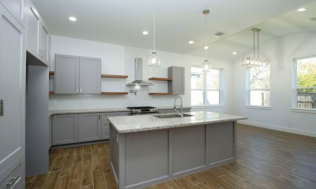 kitchen with wall chimney exhaust hood, a healthy amount of sunlight, light stone countertops, and sink