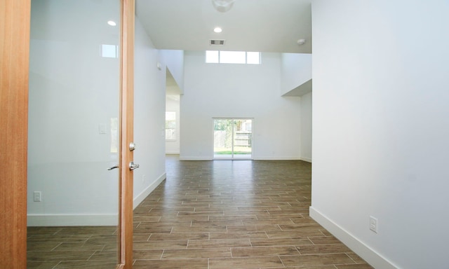 hall with hardwood / wood-style floors and a towering ceiling