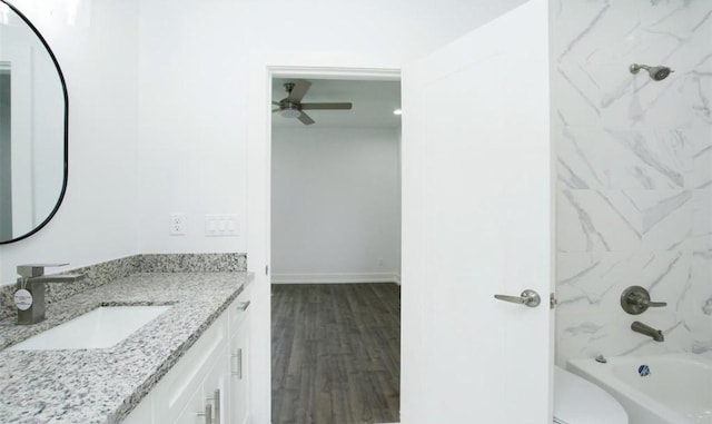 full bathroom featuring hardwood / wood-style floors, vanity, tiled shower / bath, ceiling fan, and toilet