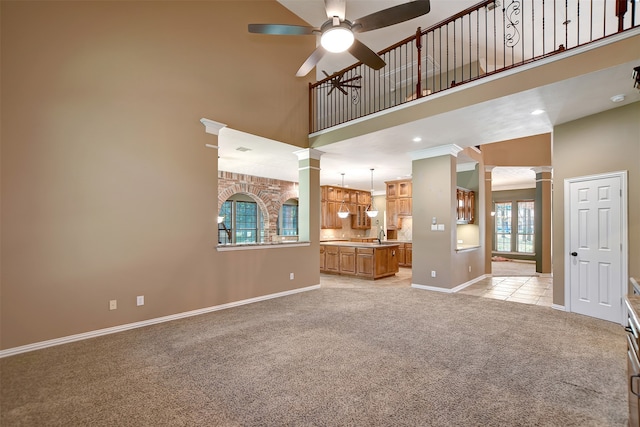 unfurnished living room with decorative columns, a high ceiling, and a healthy amount of sunlight