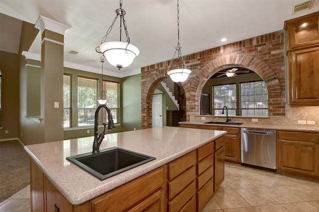 kitchen with hanging light fixtures, an island with sink, sink, and stainless steel dishwasher