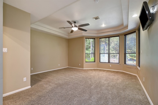 carpeted empty room with ceiling fan, crown molding, and a tray ceiling