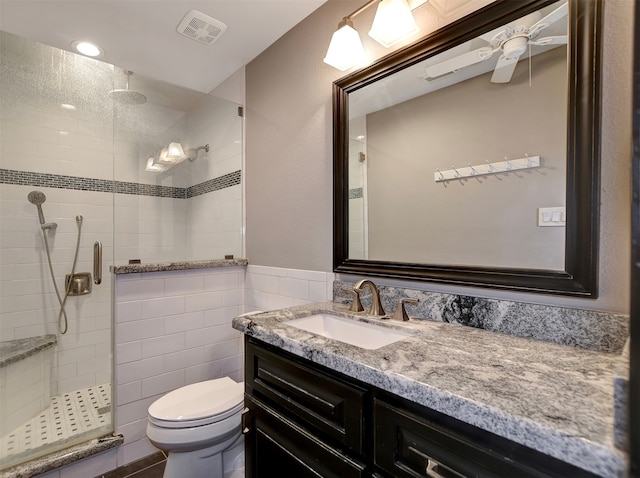 bathroom featuring an enclosed shower, vanity, tile walls, and toilet