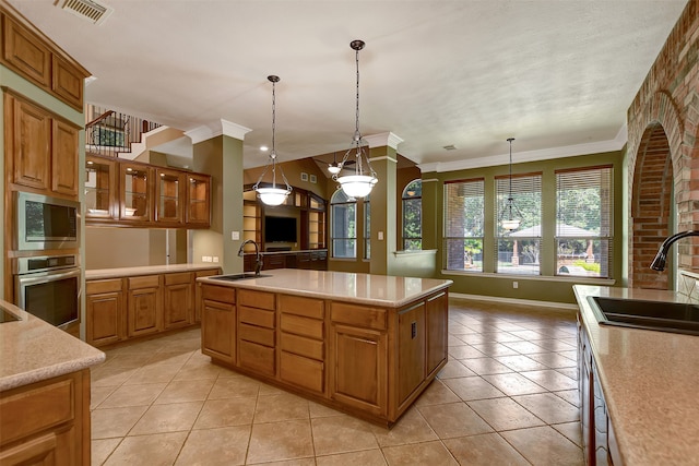 kitchen with pendant lighting, a center island with sink, stainless steel appliances, and sink