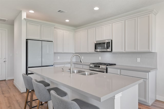 kitchen featuring white cabinetry, appliances with stainless steel finishes, sink, and a center island with sink