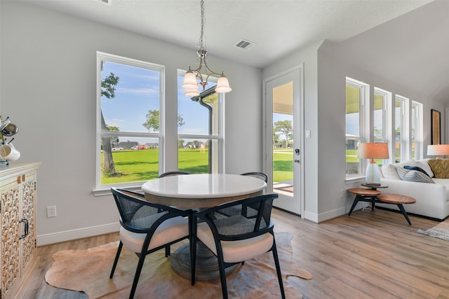 dining space with an inviting chandelier, a healthy amount of sunlight, and light wood-type flooring