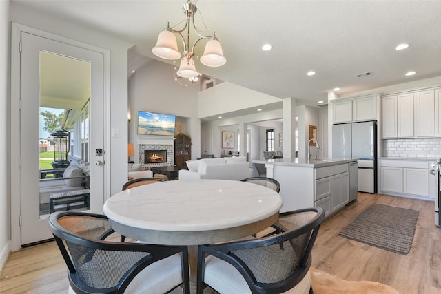 dining room with light hardwood / wood-style flooring, vaulted ceiling, sink, and a chandelier