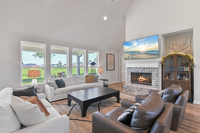 living room featuring light hardwood / wood-style floors, high vaulted ceiling, and a brick fireplace