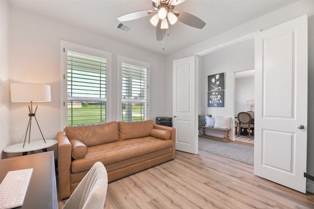 living room featuring ceiling fan, a textured ceiling, and light wood-type flooring