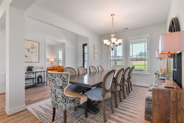 dining space with light hardwood / wood-style floors and a chandelier