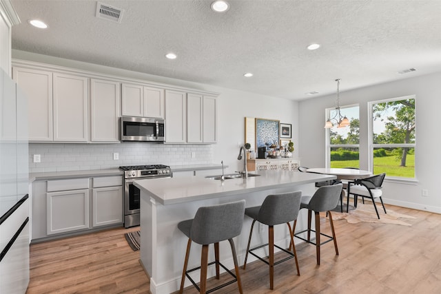 kitchen featuring appliances with stainless steel finishes, white cabinetry, and a center island with sink