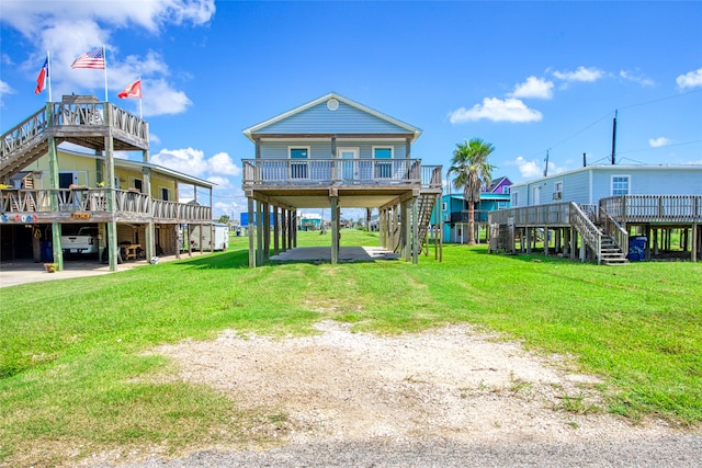 rear view of property with a deck, a lawn, and a carport