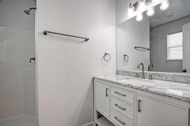 bathroom with vanity and a shower