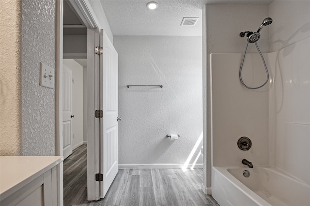 bathroom featuring vanity, a textured ceiling, hardwood / wood-style flooring, and bathing tub / shower combination