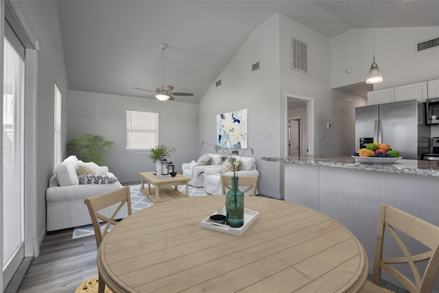 dining room featuring high vaulted ceiling, light wood-type flooring, and ceiling fan