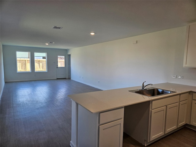 kitchen featuring kitchen peninsula, white cabinetry, dark wood-type flooring, and sink