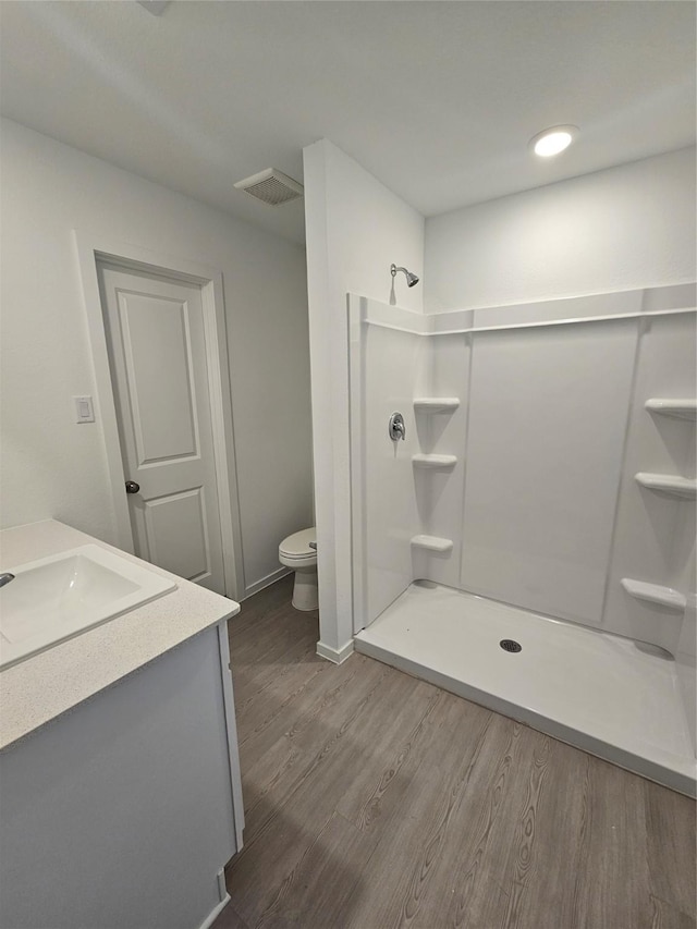 bathroom with walk in shower, toilet, vanity, and hardwood / wood-style flooring