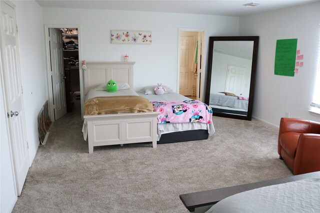 bedroom with a spacious closet, light carpet, and a closet