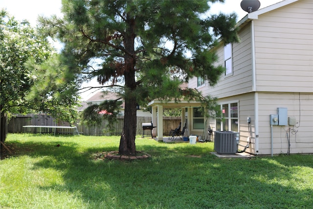 view of yard featuring a trampoline, a patio area, and central air condition unit