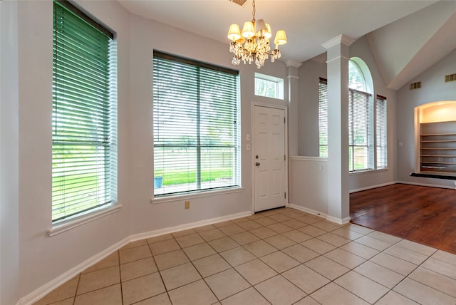 entrance foyer featuring lofted ceiling, a healthy amount of sunlight, a notable chandelier, and light tile patterned floors