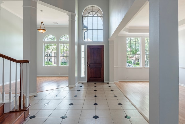 entryway with ornamental molding, ornate columns, and light hardwood / wood-style floors