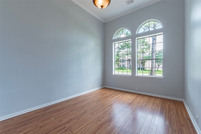 spare room with ornamental molding and light hardwood / wood-style flooring