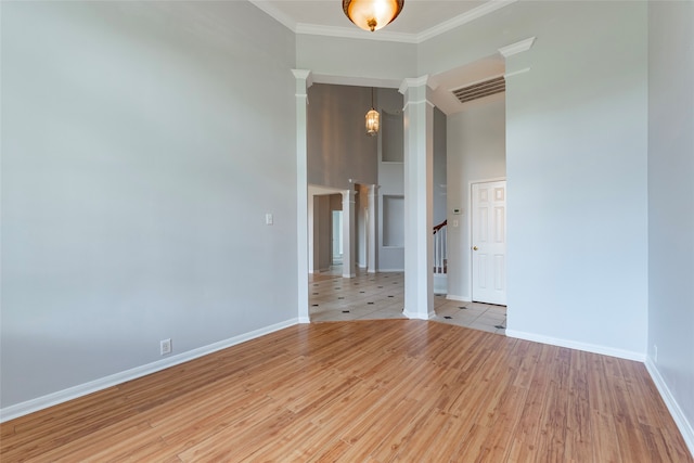 unfurnished room with ornamental molding, a high ceiling, ornate columns, and light wood-type flooring