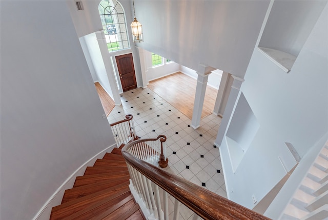 staircase featuring decorative columns and wood-type flooring